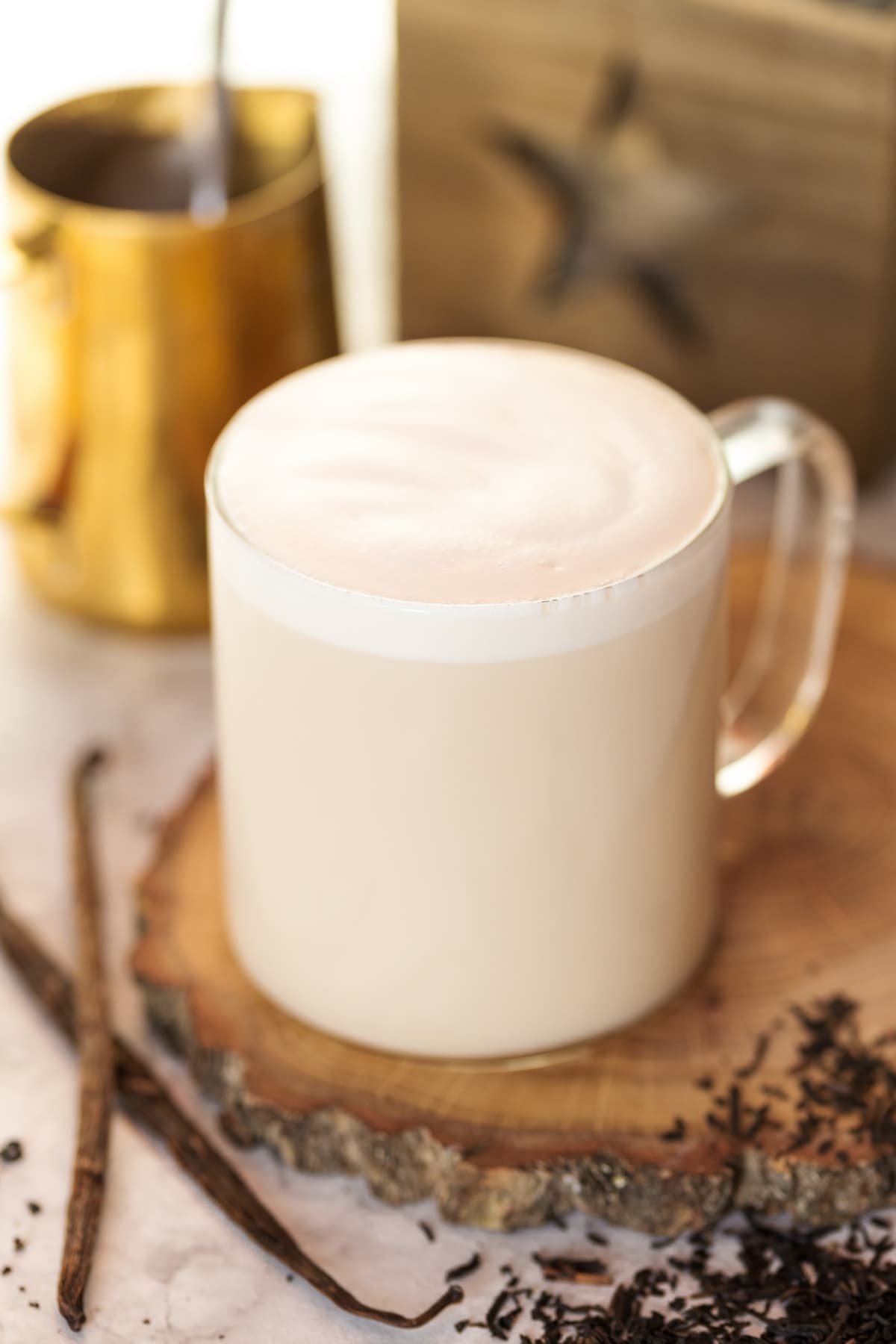 London Fog tea latte with loose leaf tea and vanilla beans placed next to it.