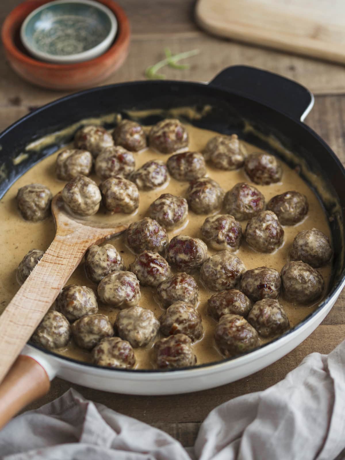 Small meatballs in cream gravy in a skillet.