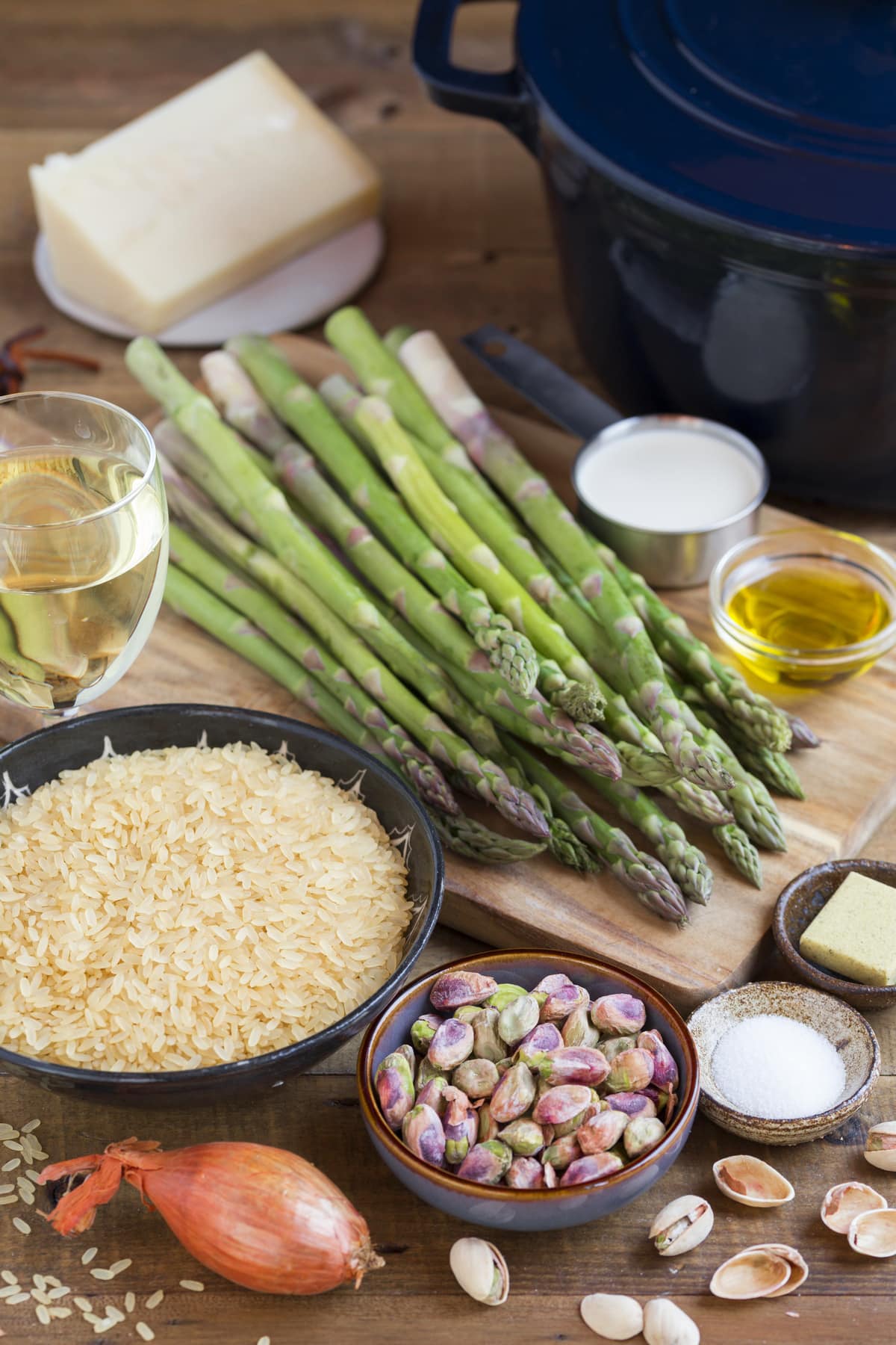 Asparagus stalks on a wooden board surrounded by other ingredients needed for the recipe.
