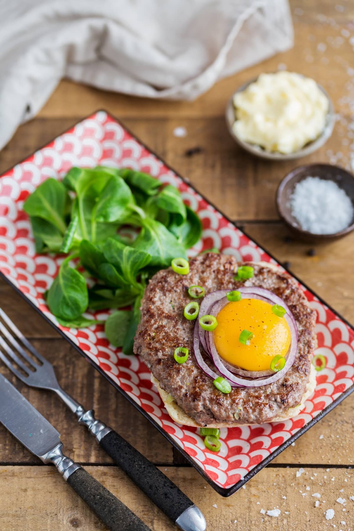 Raw egg yolk topping beef patty open sandwich.