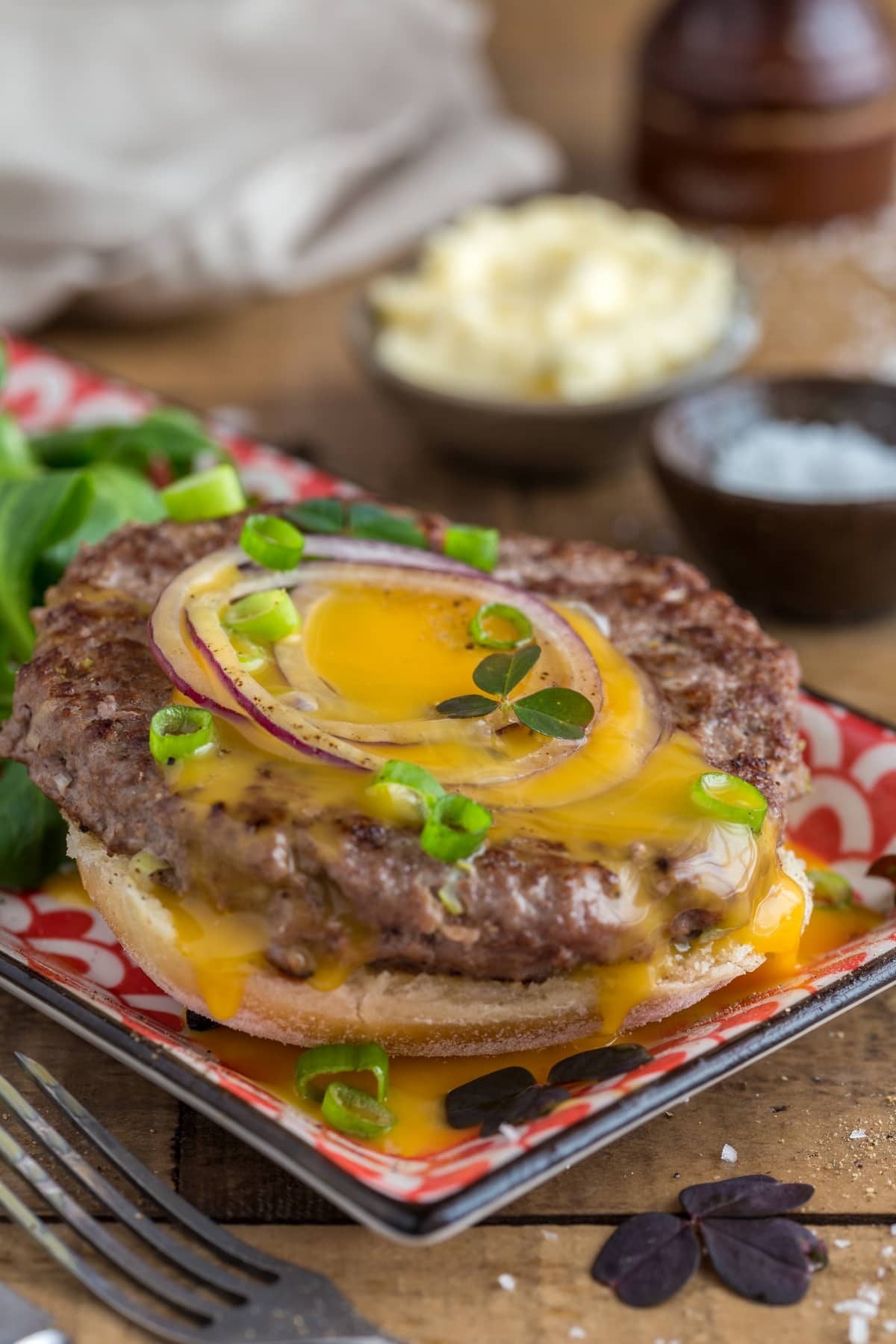 Beef patty open sandwich topped with raw egg yolk.