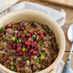 Crispy bacon and fresh spring onion topping a portion of lentil stew.