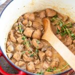 Cream cheese chicken and mushrooms stew in a red Dutch oven pot.