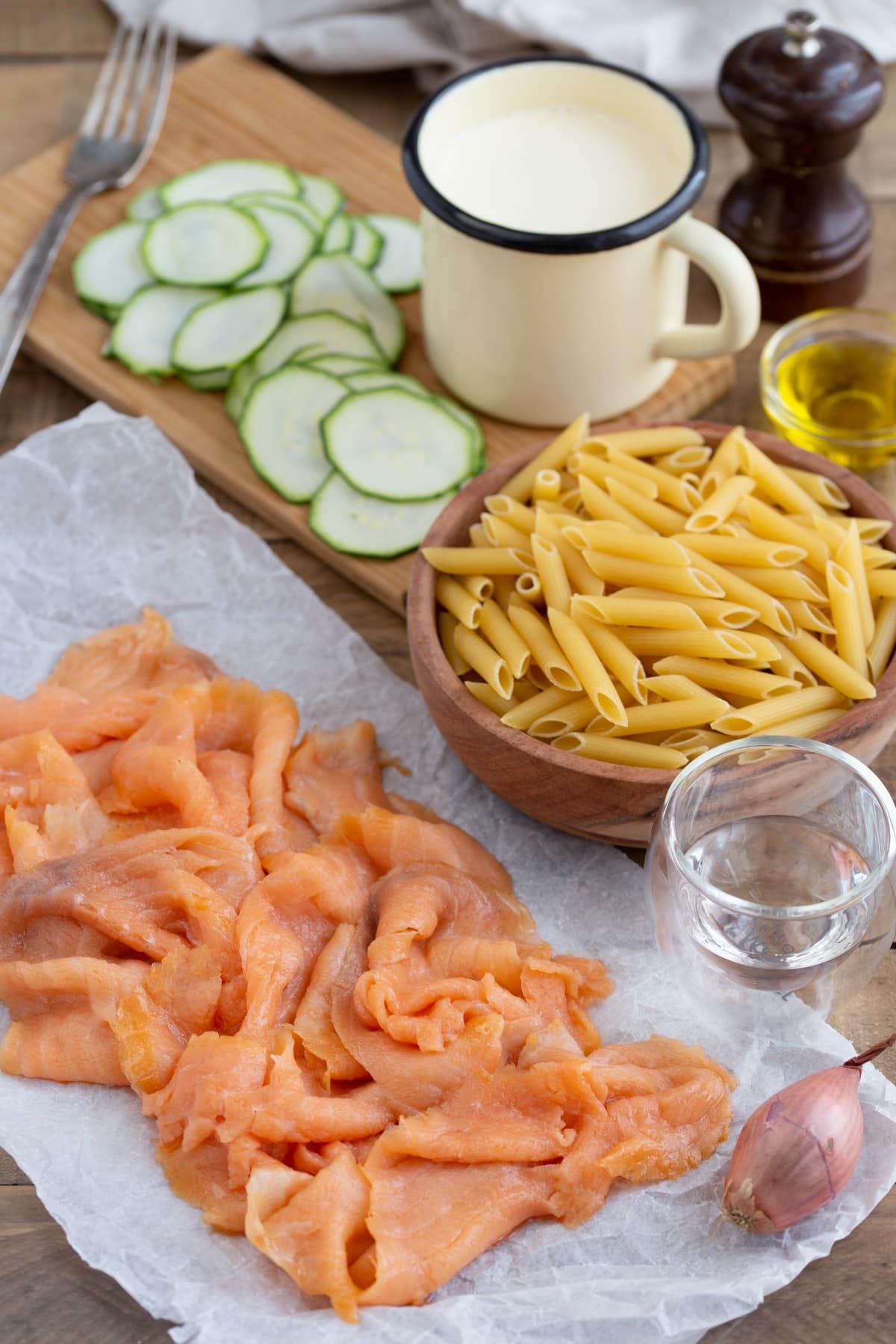 Ruffled slices of smoked salmon surrounded by other ingredients needed for the recipe.