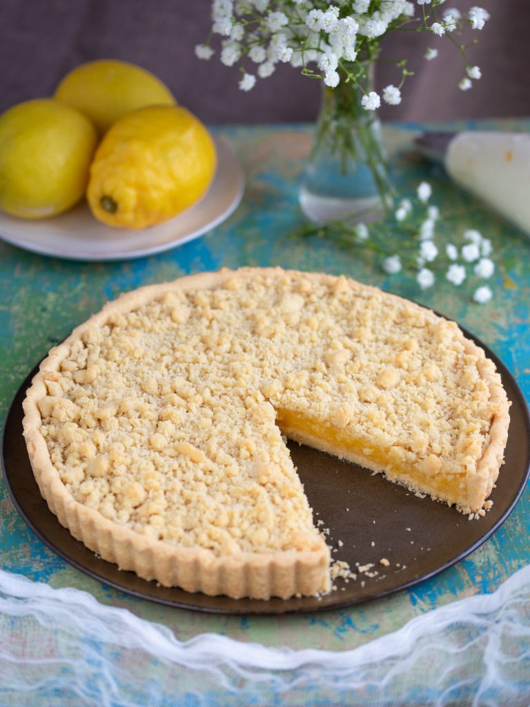 Ginger lemon pie on brown plate, one slice missing.