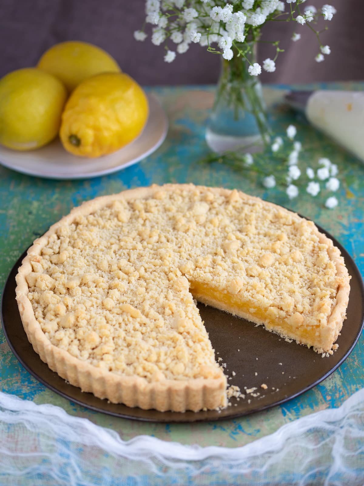 Ginger lemon pie on brown plate, one slice missing.