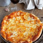 Cheese pizza served with a glass of red wine.