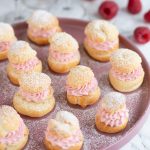 Raspberry cream puffs on a pink plate.
