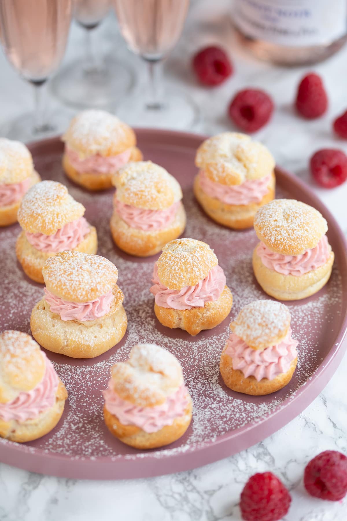 Raspberry cream puffs on a pink plate.