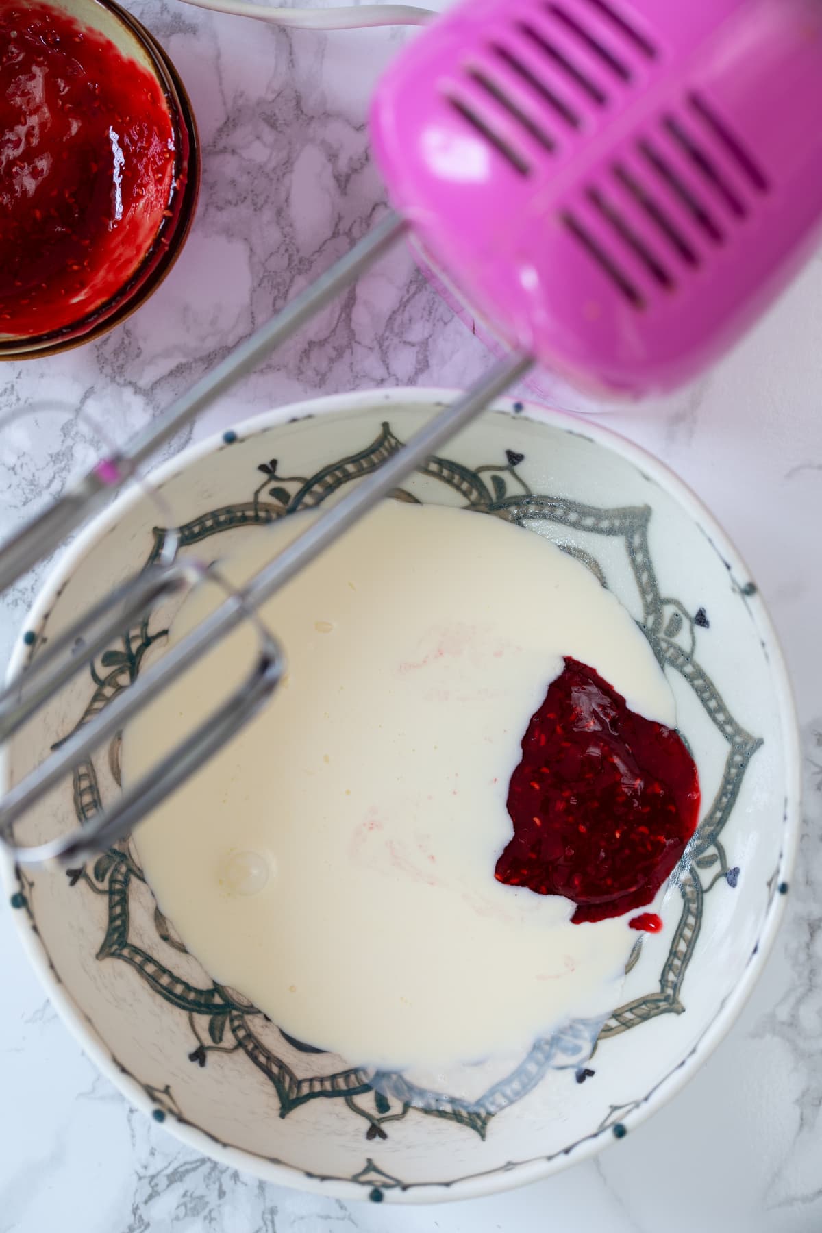Combining raspberry purée and whipping cream.