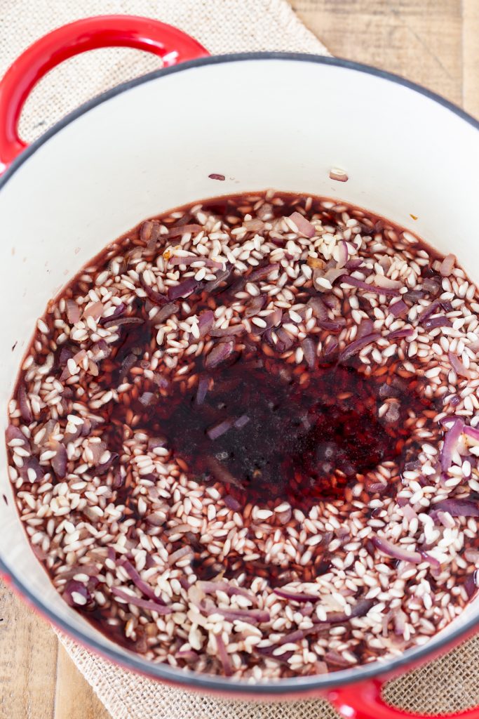 Adding red wine to toasted rice.