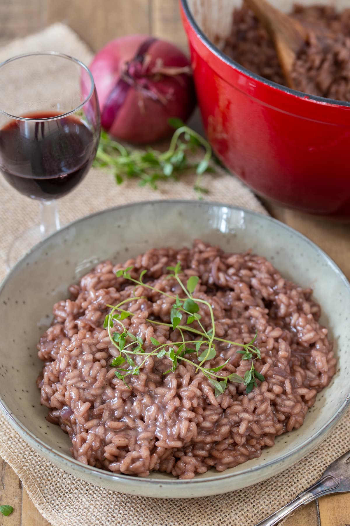 Red wine risotto served in a beige bowl.