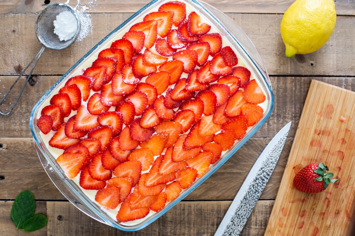 Topping the tiramisu with fresh strawberries and powdered sugar.