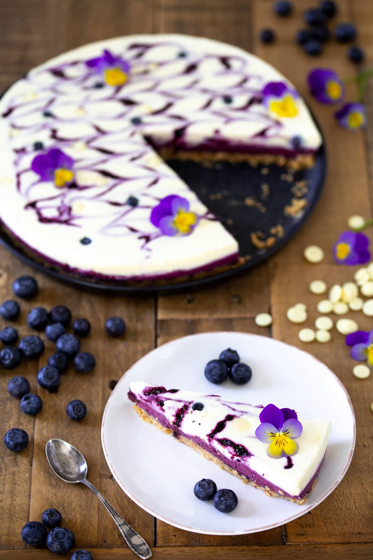 A slice of blueberry no-bake cheesecake with edible flowers.