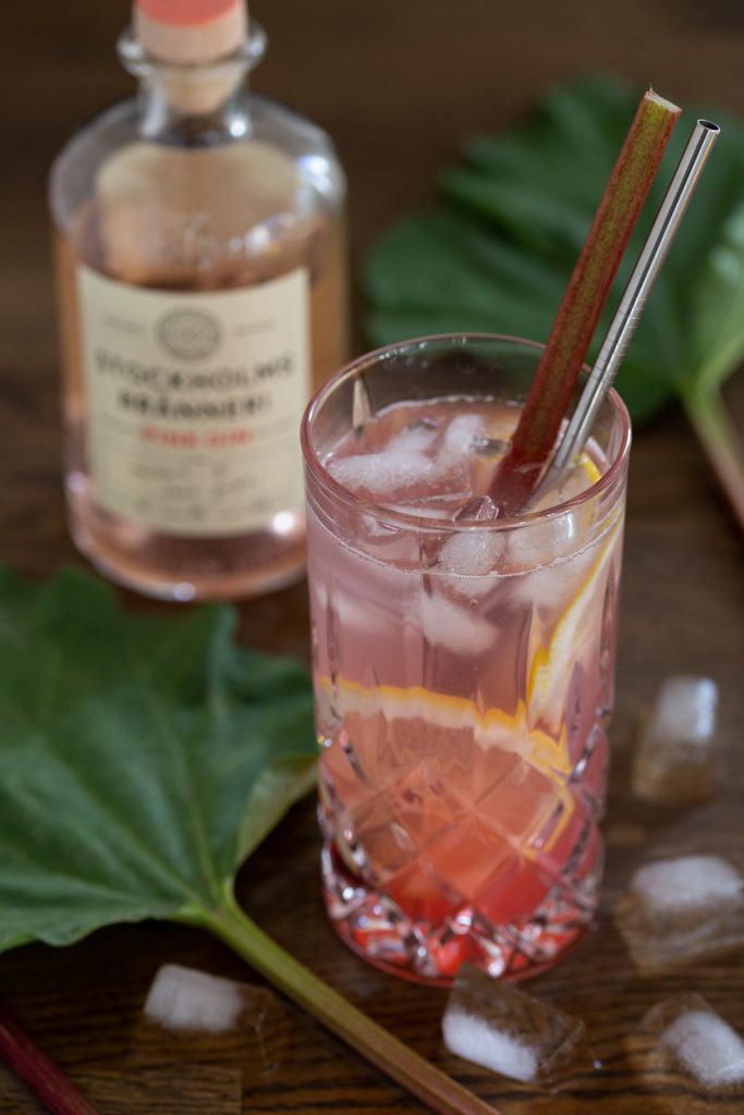 A glass of rhubarb gin and tonic with the bottle of Pink Gin in the background.