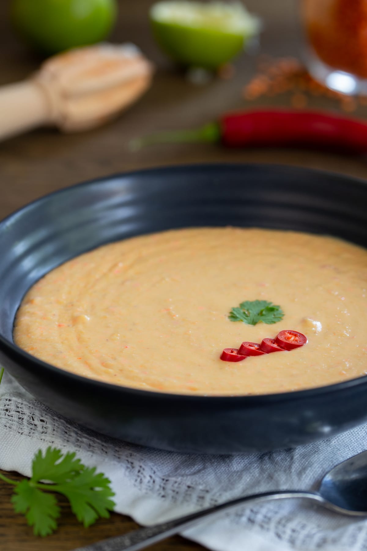 Soup topped with sliced chili and a cilantro leaf.