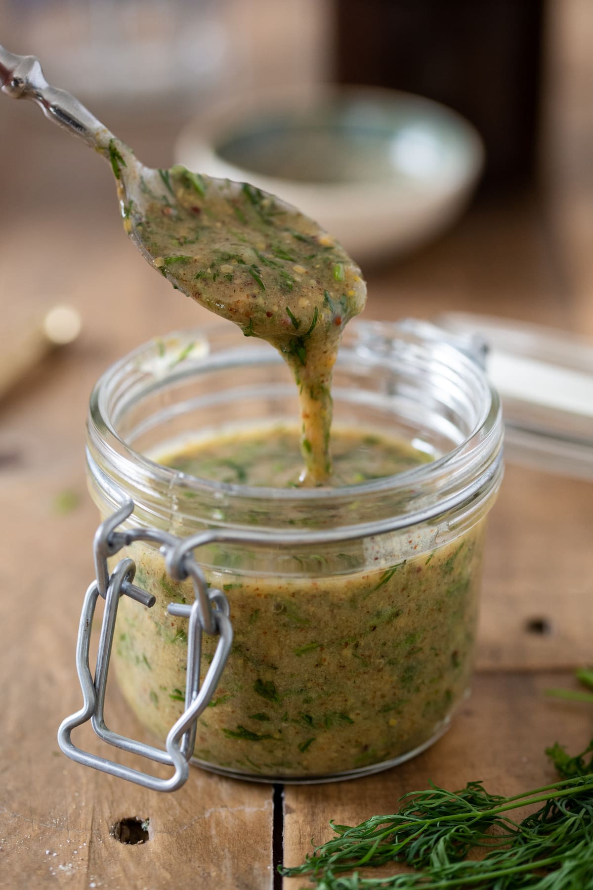 Dill mustard sauce pouring from a spoon to show the consistency.