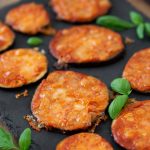 Eggplant pizza bites on a black tray.
