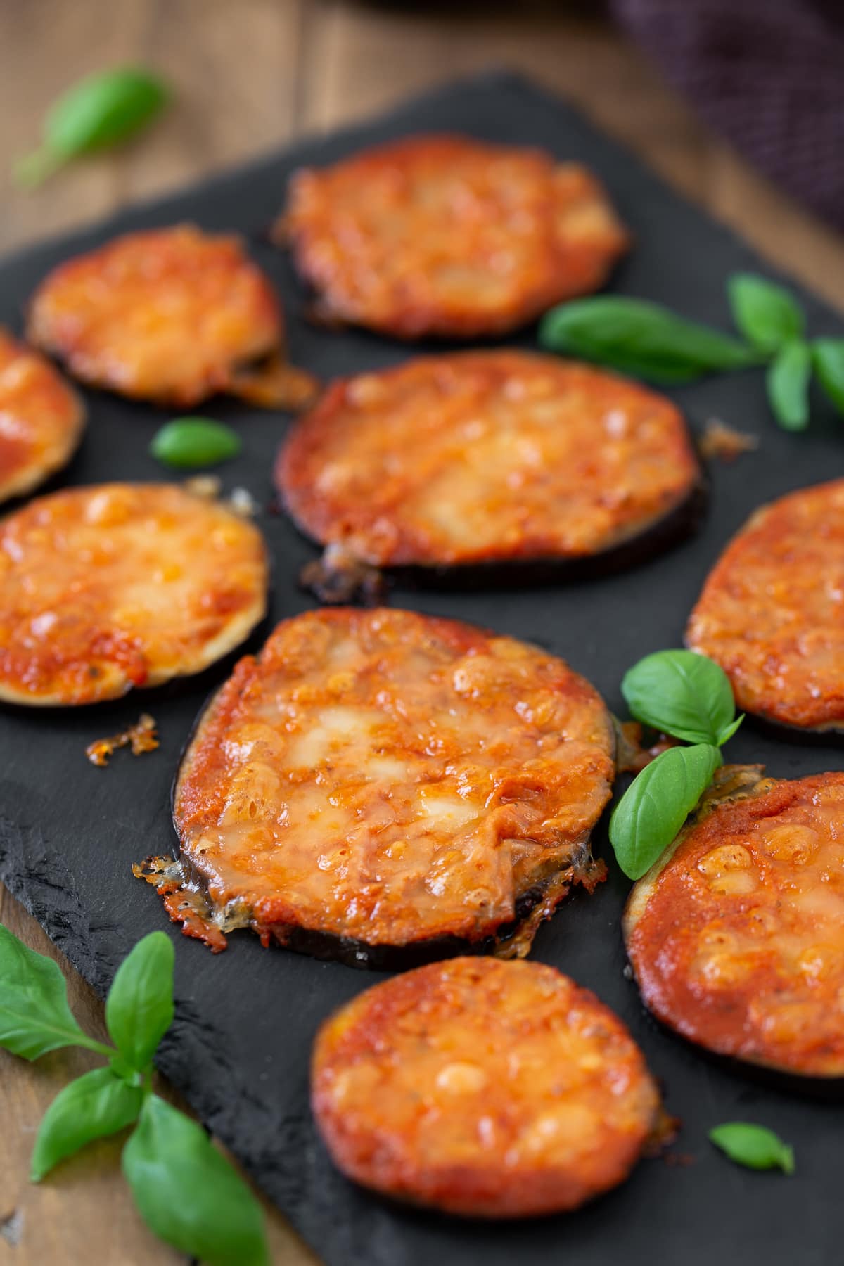 Eggplant pizza bites on a black tray.