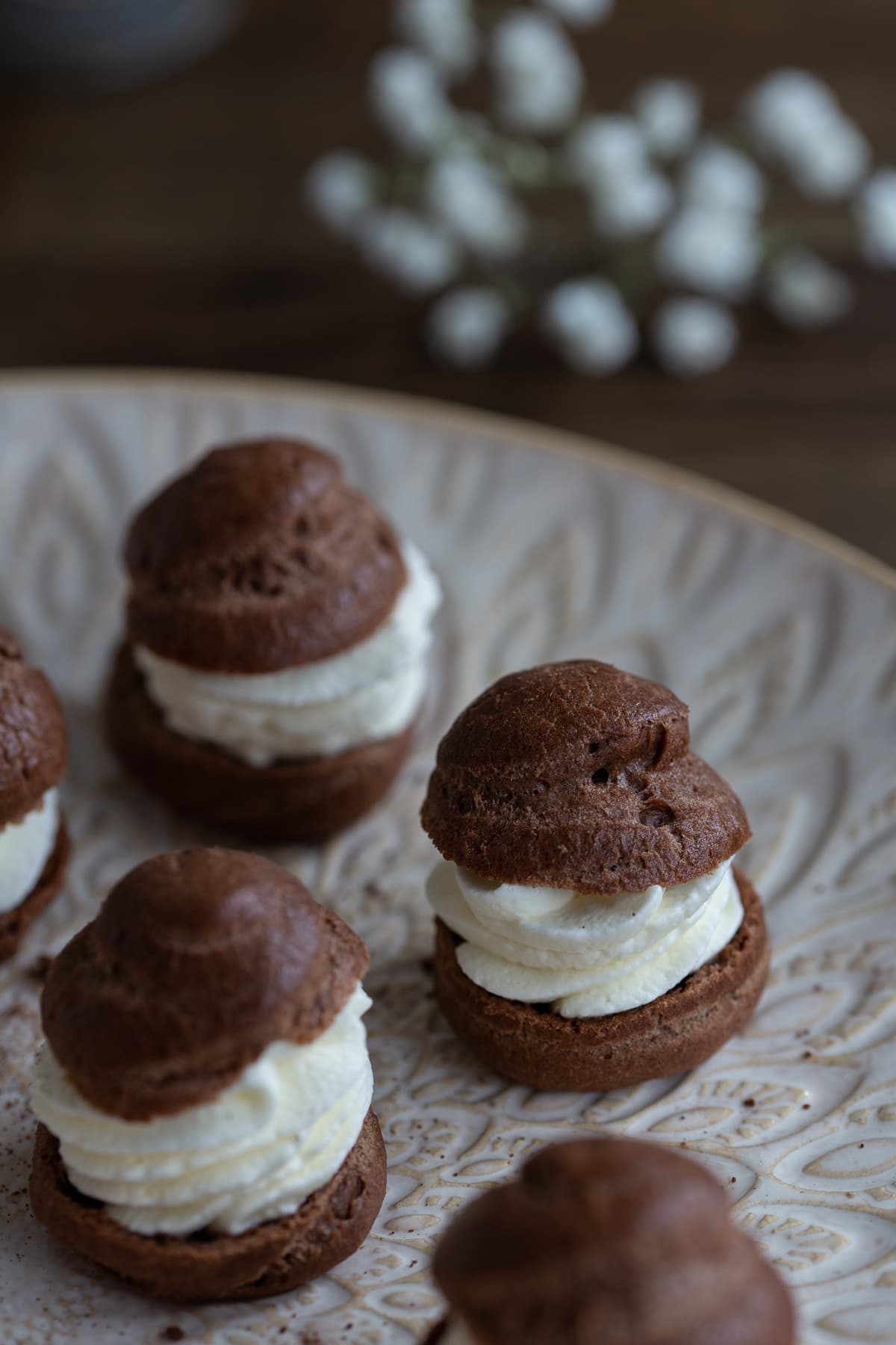 Chocolate cream puffs on a white plate.