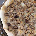 Overhead view of garlic mushroom pizza bianca made with baby bella mushrooms.