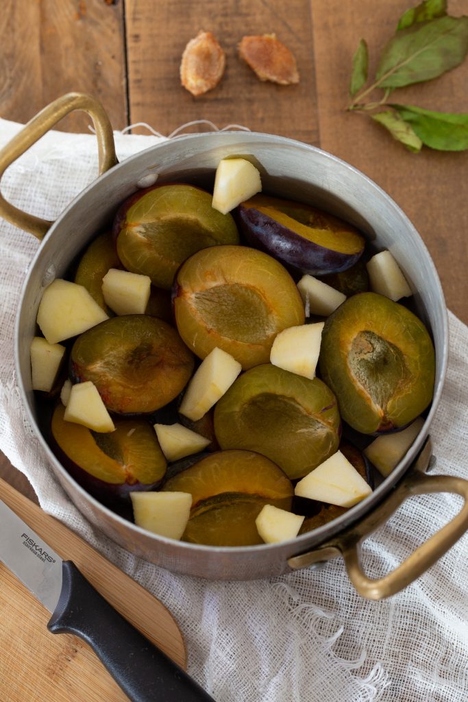 Plums and apple in a pot.