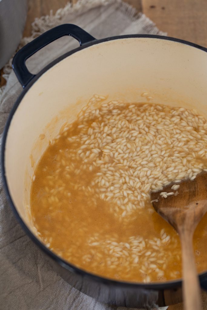 Adding beef stock to cook the rice.