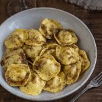 A portion of cheese ravioli with hazelnut butter in a white bowl.