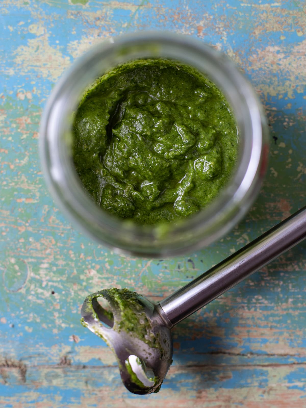 Overhead view of pesto in a jar and immersion blender on the side.
