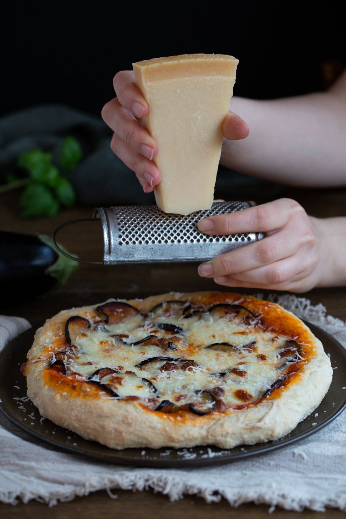 Grating parmesan on top of eggplant pizza.