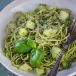 A portion of pesto pasta with potatoes in a white bowl.
