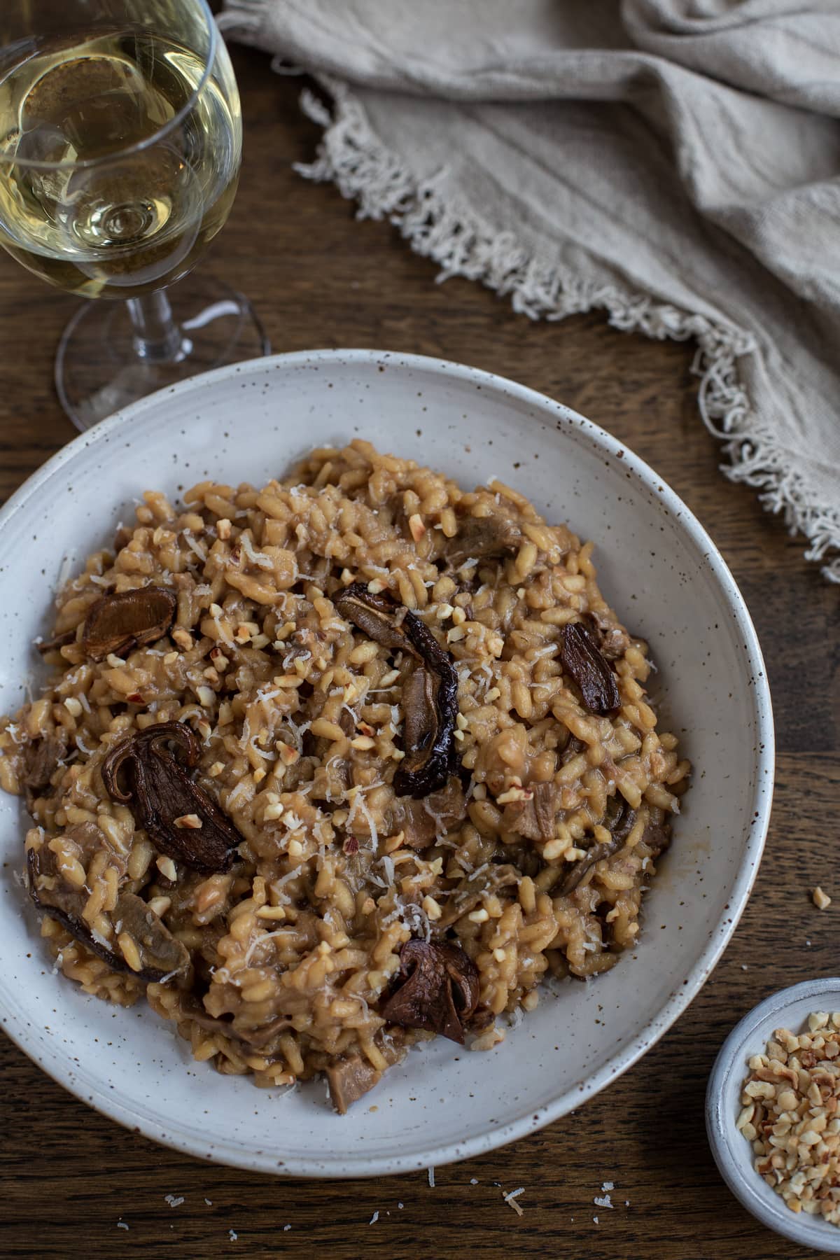 Dried porcini risotto with hazelnuts served in a white bowl.