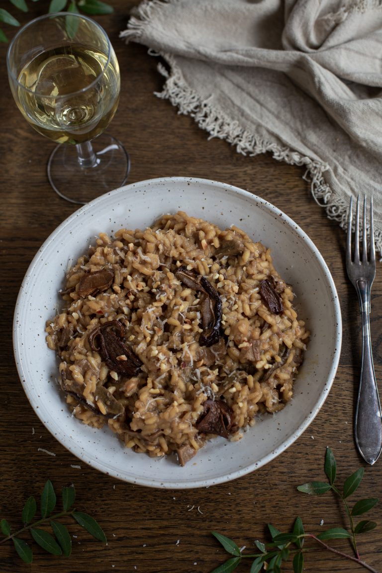 Dried porcini risotto with hazelnuts served in a white bowl.