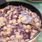 Radicchio gnocchi with cream in a skillet.