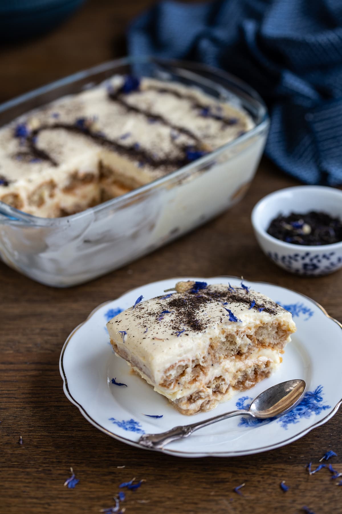 A portion of tiramisu on a white and blue plate.