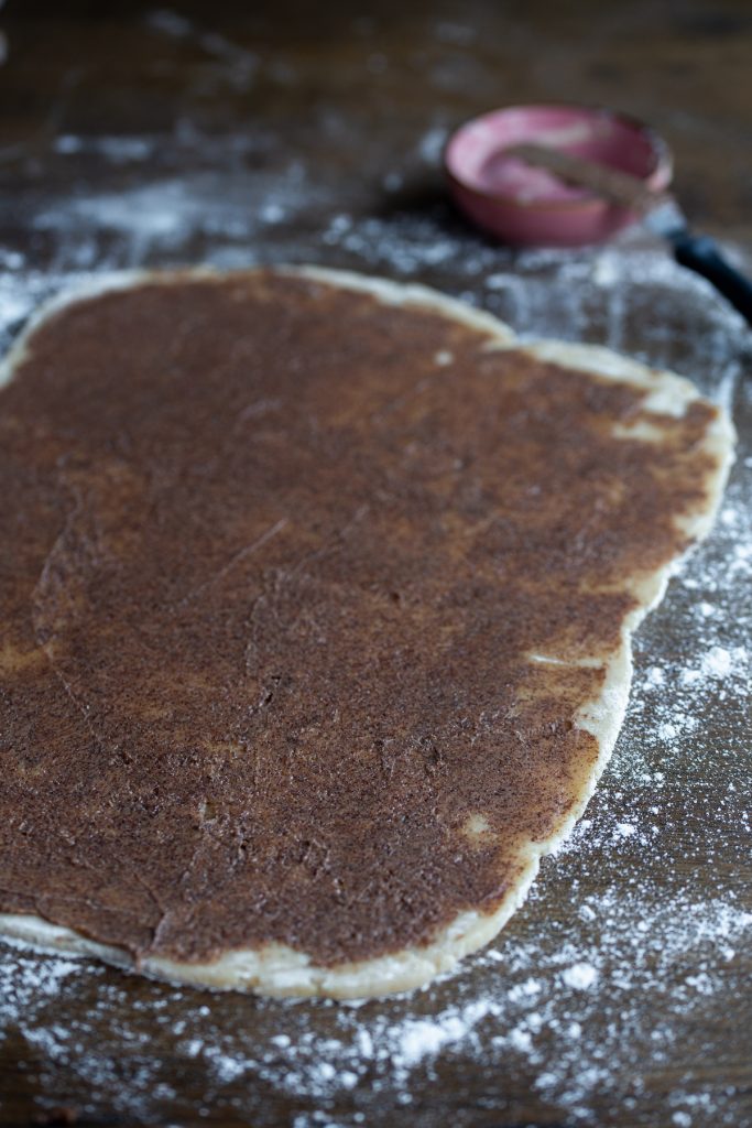 Cinnamon filling spread on rolled-out dough.