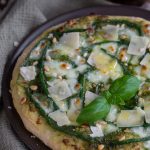 Pesto pizza with green beans topped with pine nuts and parmesan flakes.