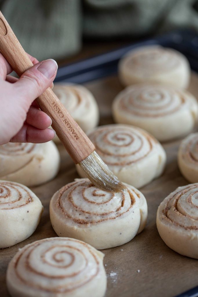 Brushing eggwash over unbaked Swedish cinnamon buns.