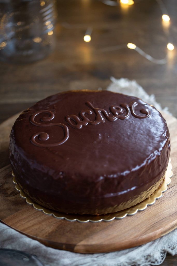 Sachertorte covered in ganache showing the classic "Sacher" decorative writing on top.