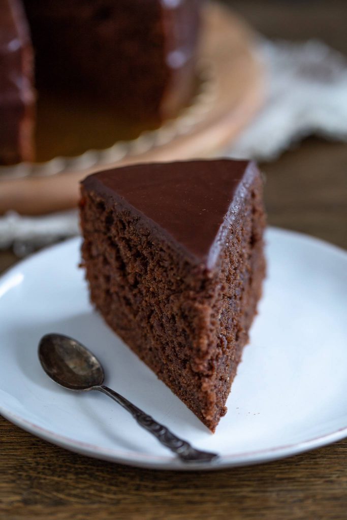 a slice of chocolate sacher torte on a plate with a spoon.