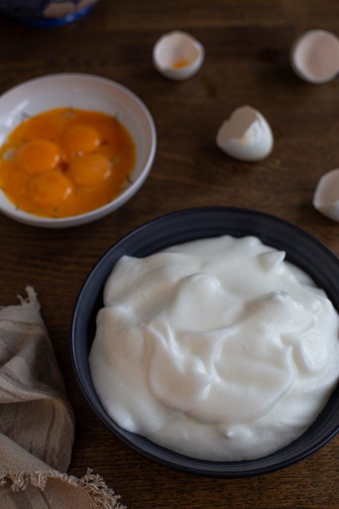 Whipped egg whites in a bowl, yolks in another.