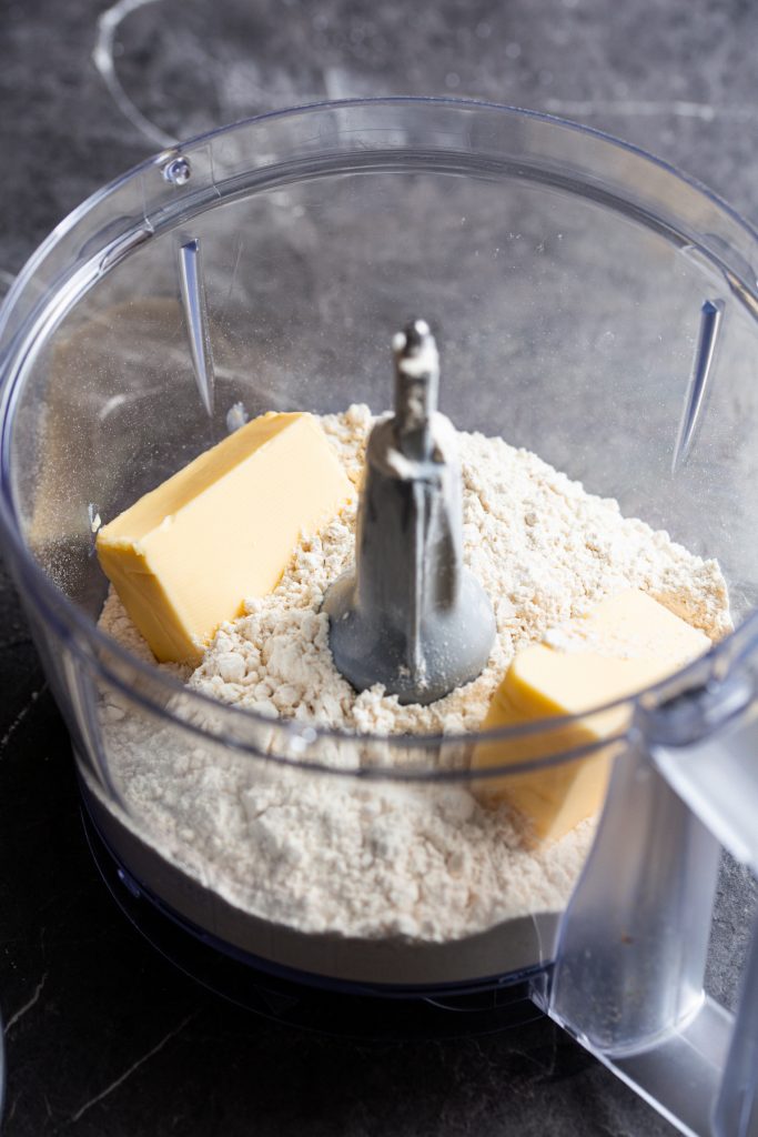 Inside of food processor showing flour and butter.