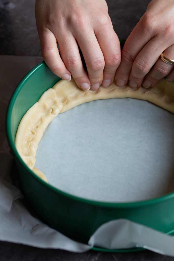 Hands pressing pie dough into pan.