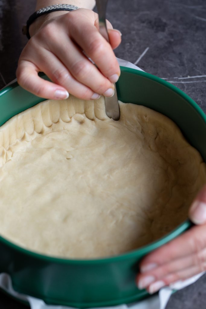 Hands pressing pie dough into pan.