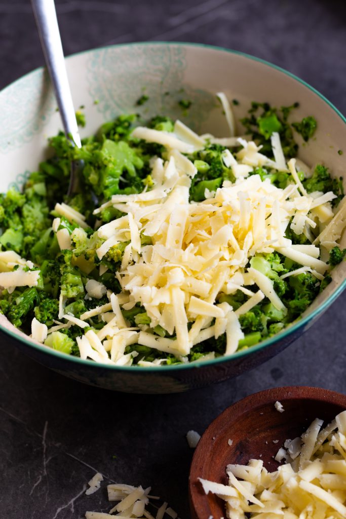Grated cheese added to a bowl with broccoli.