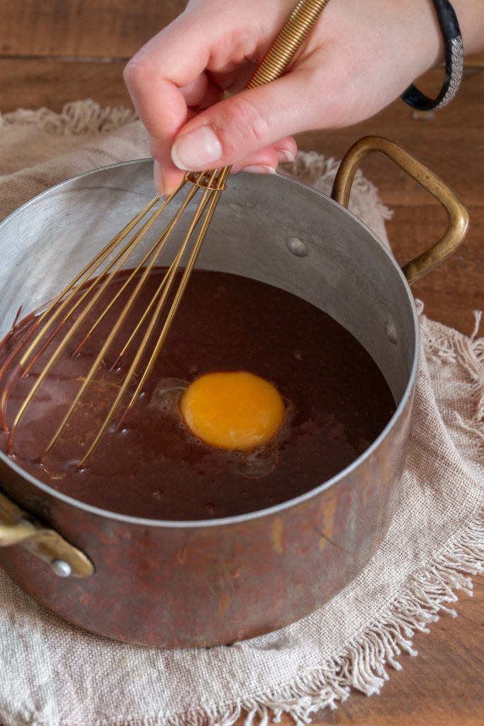 Whisking an egg yolk into chocolate mixture.