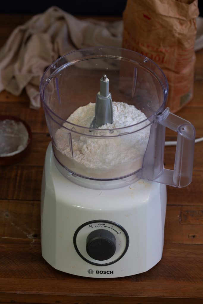 Food processor with flour and powdered sugar inside.