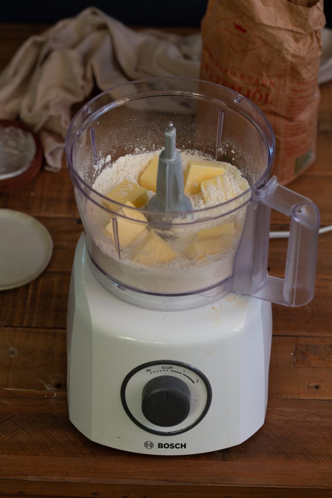 Adding butter to flour mix in food processor.