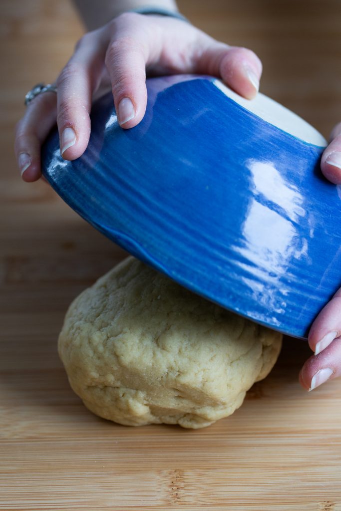 Blue bowl placed over pasta dough ball.