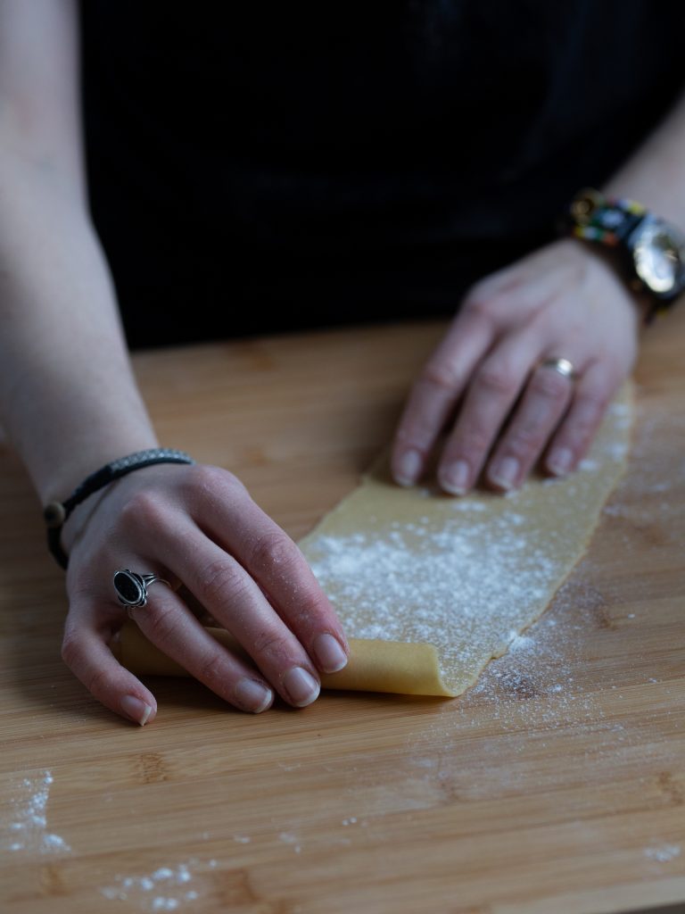 Rolling up a thin sheet of pasta.